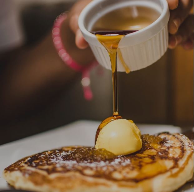 Maple syrup being poured on pancakes